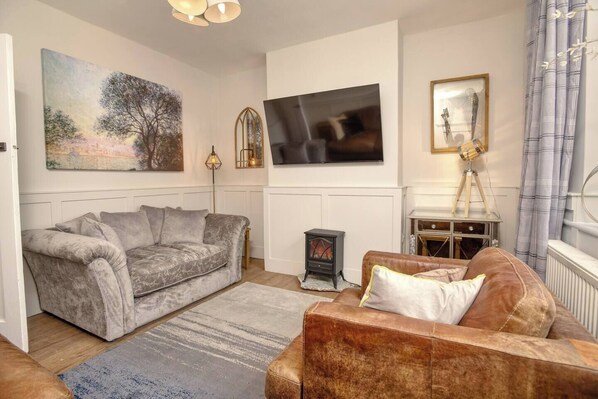 A living room with a grey sofa, a brown leather sofa, a fireplace, and a large painting on the wall.