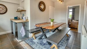 Cozinha moderna com mesa de jantar, banco embutido e uma pequena ilha com pia e espaço para armazenamento.
