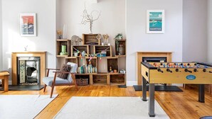 A cozy living room with a foosball table, a fireplace, and a bookshelf filled with books and decorative items.