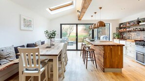 A modern kitchen with a central island, wooden flooring, and skylights.