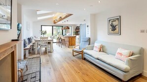 A modern living room with a sofa, dining area, and kitchen in the background.