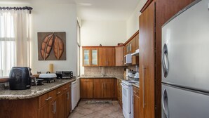 Una cocina con armarios de madera, un refrigerador de acero inoxidable, un microondas y una cafetera.
