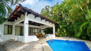 A poolside area with a white building, a covered patio, and a clear blue pool. - Villas Sol 21 Serenity Place at Playa Hermosa (Playa Hermosa)