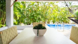 A poolside area with a table, chairs, a hanging hammock, and a potted plant. - Villas Sol 21 Serenity Place at Playa Hermosa (Playa Hermosa)