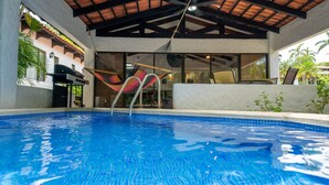 Ein Swimmingpool mit Hängematte, Sitzgelegenheiten im Innenbereich und Blick ins Freie.