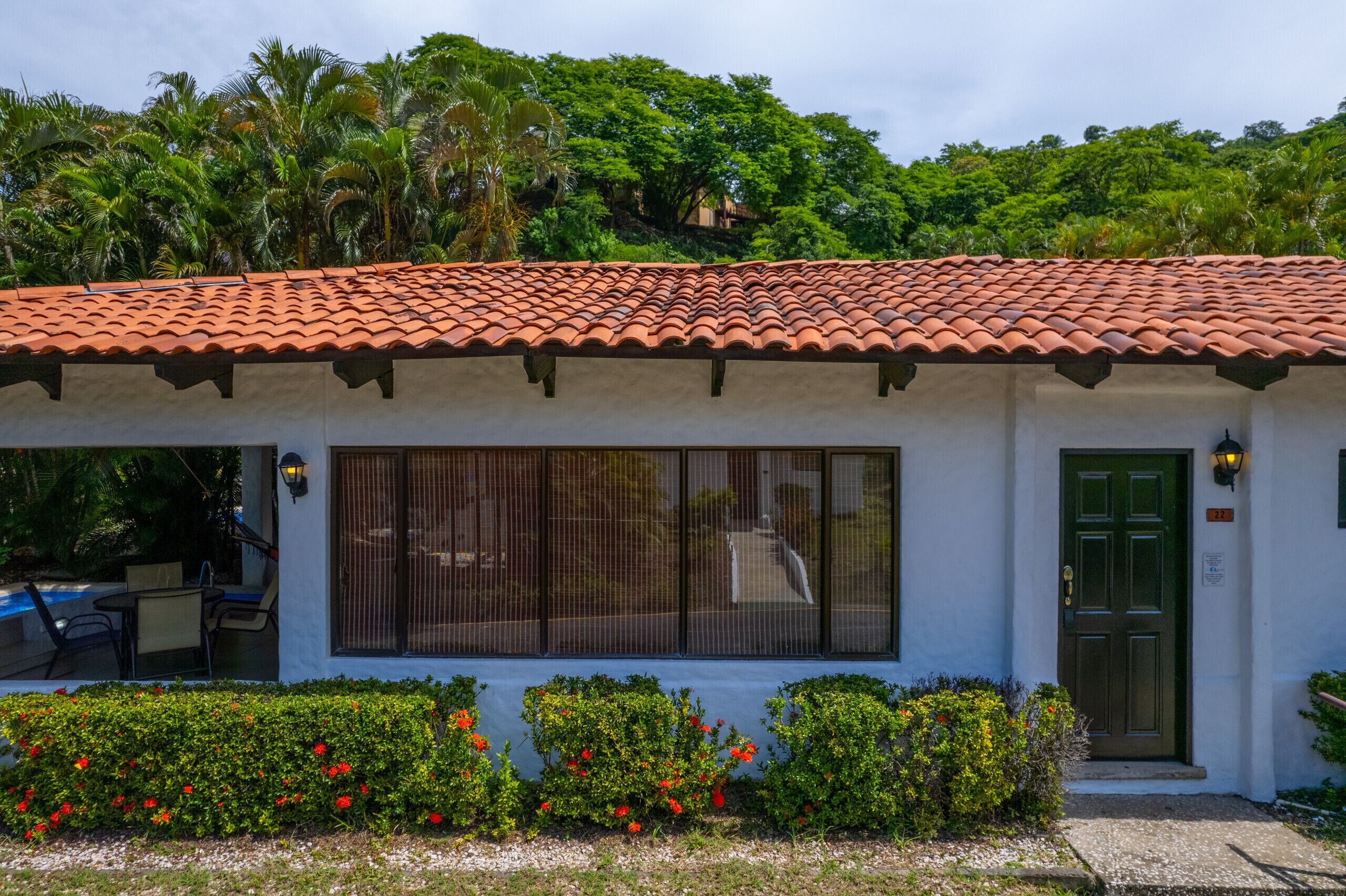 A building with a tiled roof, a green door, and a window with a view of a road.