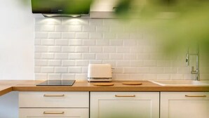 A modern kitchen with white cabinets, a wooden countertop, a built-in oven, and a stainless steel faucet.