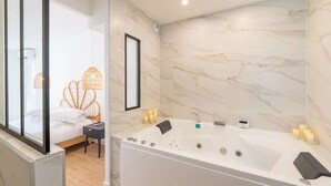 A modern bathroom with a large bathtub, a mirror, and a bed with a unique headboard.
