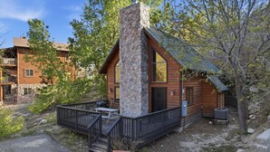 A cabin with a stone chimney, wooden exterior, and a fenced deck area. - The Family Bear Cabin at Mt. Lemmon Hotel (Mount Lemmon)
