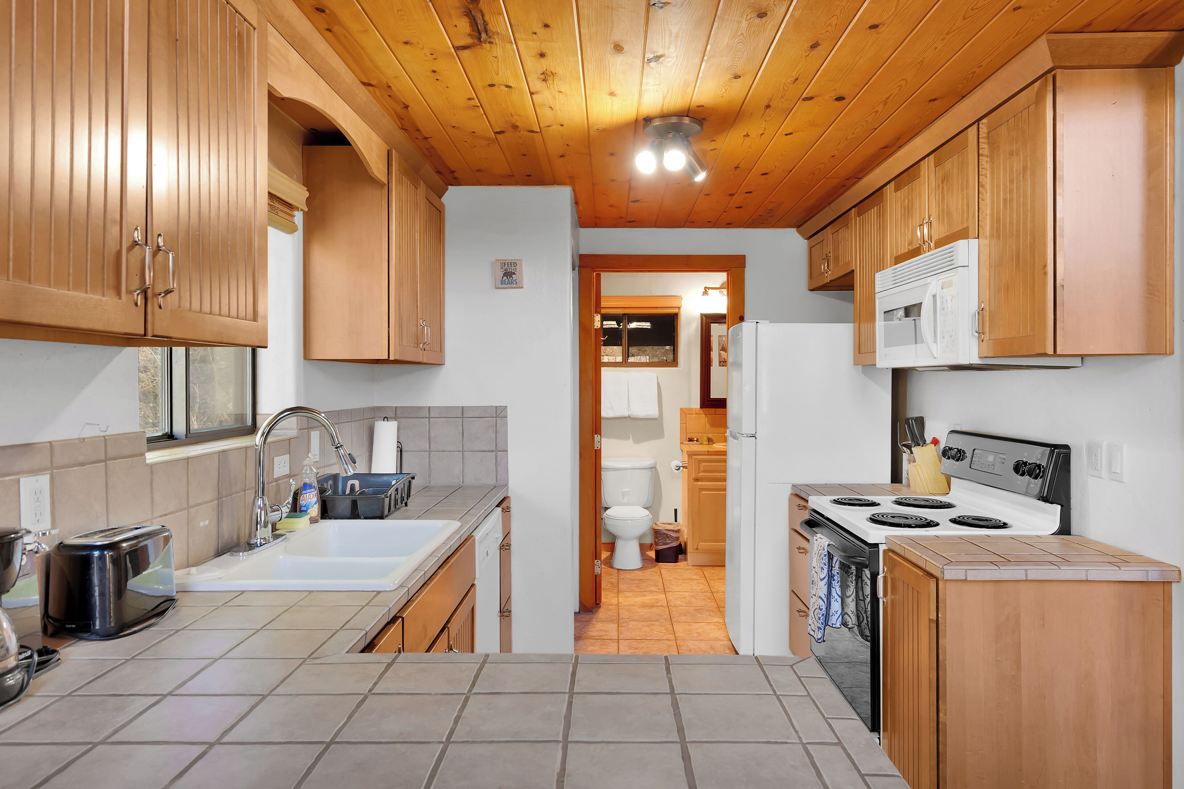 A kitchen with wooden cabinets, a stove, and a sink.