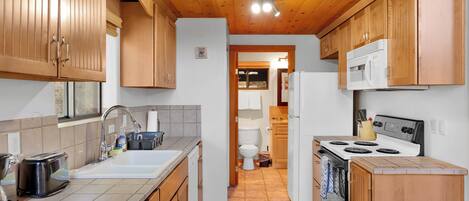 A kitchen with wooden cabinets, a stove, and a sink.
