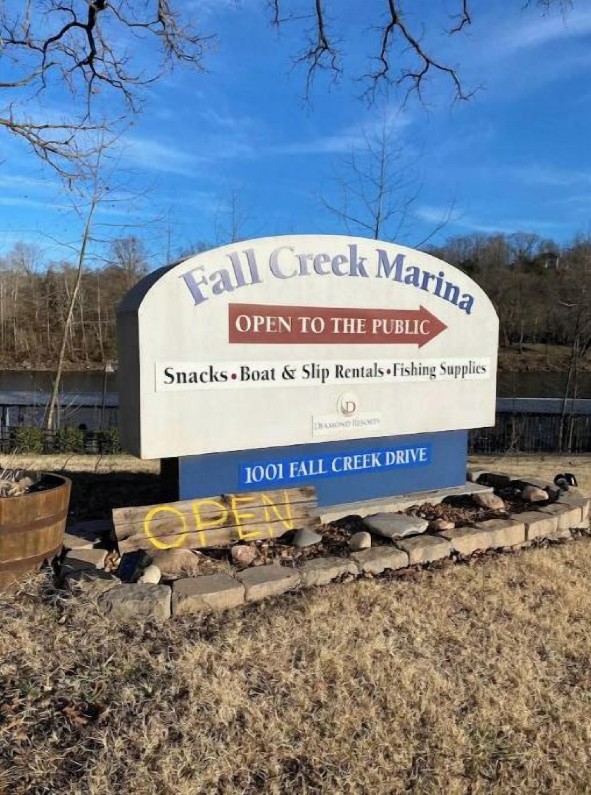 Señal para el Puerto Deportivo Fall Creek indicando que está abierto al público y ofrece aperitivos, alquiler de embarcaciones y muelles, además de artículos de pesca.