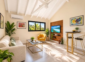 A modern living room with a sofa, a yellow armchair, a coffee table, and a TV mounted on a wooden wall.