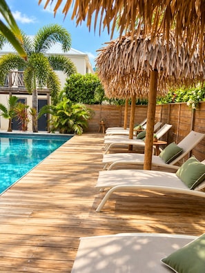 Une terrasse en bois avec des chaises longues et une piscine.