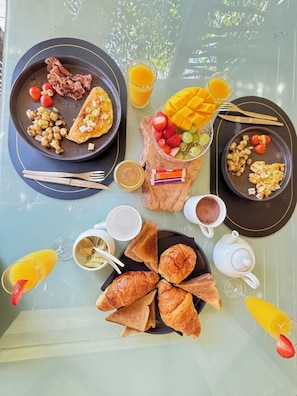 Une table de petit-déjeuner avec des assiettes d’œufs, des toasts et des fruits, ainsi qu’une théière et des tasses.