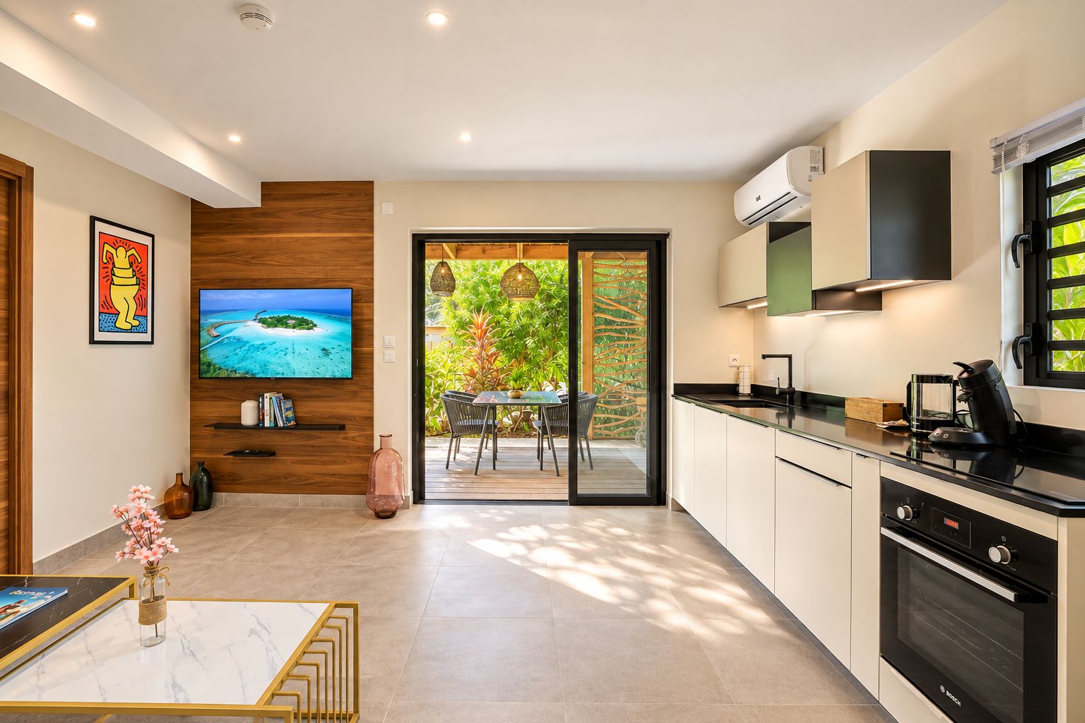Cozinha moderna com uma televisão grande, área de refeições com vista e porta de vidro deslizante para área externa.