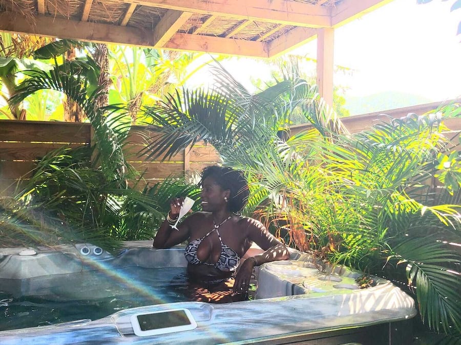 Una persona en un jacuzzi rodeado de exuberante vegetación tropical.