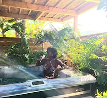 Una persona en un jacuzzi rodeado de exuberante vegetación tropical.