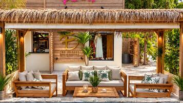 Zona junto a la piscina con terraza de madera, asientos de descanso y un cartel que dice 'Welcome to Paradise'.