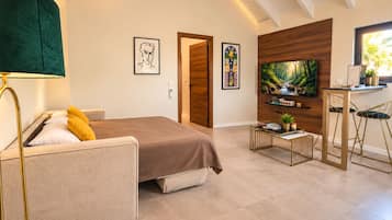 Un dormitorio moderno con una cama, un escritorio con dos sillas, un televisor y obras de arte en las paredes.