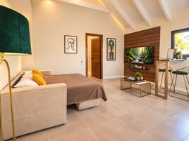 Un dormitorio moderno con una cama, un escritorio con dos sillas, un televisor y obras de arte en las paredes.