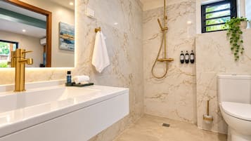 A modern bathroom with a marble wall, a gold showerhead, and a toilet.