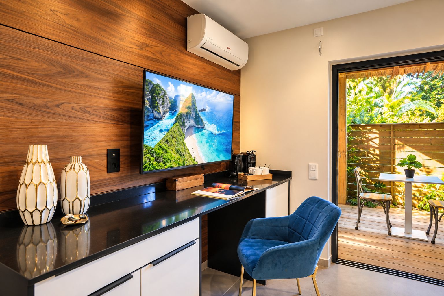 A modern kitchen with a flat-screen TV, wooden cabinetry, and a blue chair.