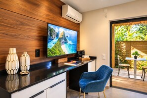 A modern kitchen with a flat-screen TV, wooden cabinetry, and a blue chair. - The Forest Suites at Anse Marcel | Boutique Hotel & Restaurant (Anse Marcel)