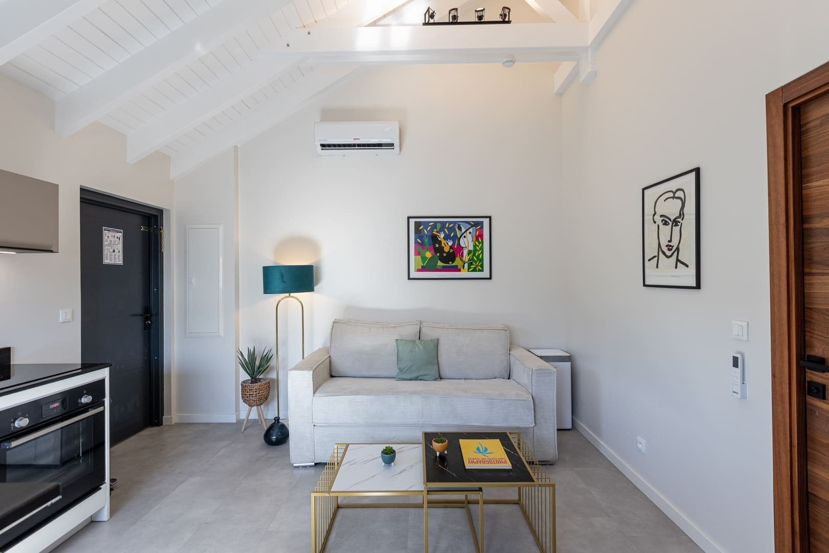 Una sala de estar moderna con un sofá, una mesa de centro, una lámpara y obras de arte en las paredes.