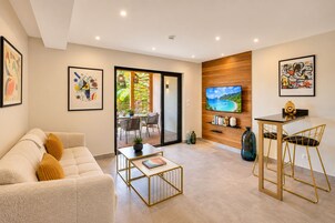 Una sala de estar moderna con un sofá, una mesa de centro y un televisor instalado en una pared de madera.