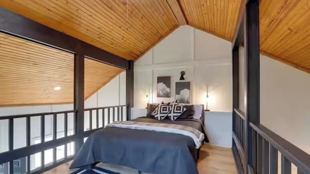 A bedroom with a sloped ceiling, a bed with a striped bedspread, and two wall-mounted lamps. - Chic Cabin! Less than 10 minutes from Downtown Siloam Springs (Gentry)