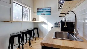 Une cuisine moderne avec un plan de travail en bois, un évier en acier inoxydable et des tabourets de bar noirs.