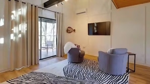 A modern living room with a zebra-patterned rug, a large window with curtains, a mounted fish decoration, and a flat-screen TV on the wall. - Chic Cabin! Less than 10 minutes from Downtown Siloam Springs (Gentry)