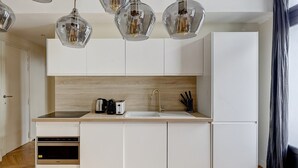 Une cuisine moderne avec des meubles blancs, une cuisinière en acier inoxydable, un évier et une machine à café.