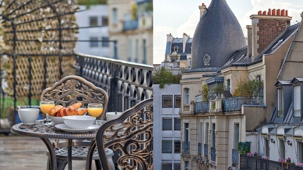 Une table à manger dressée avec des aliments pour le petit-déjeuner, et en toile de fond, un bâtiment doté d’un toit conique remarquable.