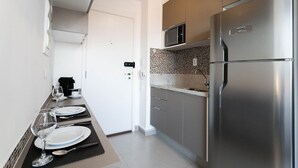 Una cocina moderna con un refrigerador de acero inoxidable, un microondas y un salpicadero de azulejos.