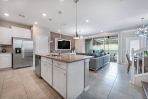 A modern kitchen with a central island, stainless steel appliances, and pendant lighting.