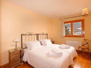 Une chambre avec deux lits, un plancher en bois, une fenêtre donnant sur un paysage agréable et un radiateur.