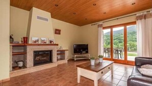 A living room with a fireplace, television, and a view of the outdoors through large sliding glass doors. - House 4 rooms 10 Pax, Fireplace, BBQ & Cadí Views (Montellà)