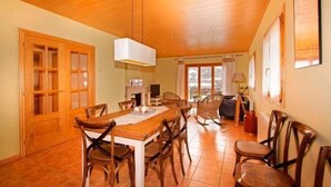 A dining area with a wooden table and chairs, a hanging light fixture, and a view of the outside through large windows. - House 4 rooms 10 Pax, Fireplace, BBQ & Cadí Views (Montellà)