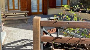 A rustic outdoor area with a stone wall, wooden benches, and a wooden fence.