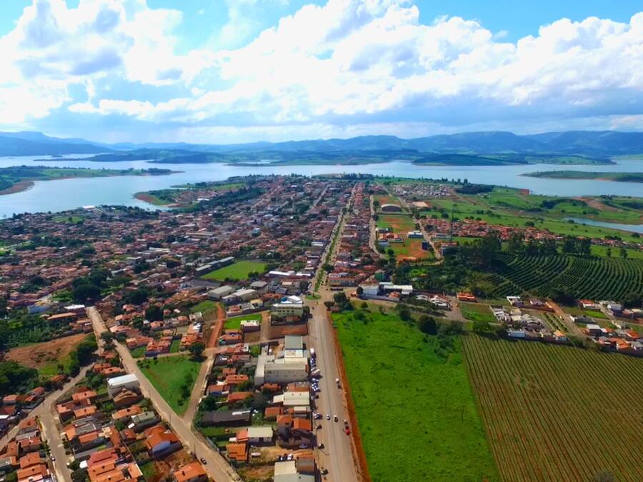 Vista aerea di una cittadina costiera con un fiume, campi verdi e un mix di edifici residenziali e commerciali.