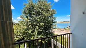 A balcony with a view of a tree and a body of water. - SAO FRANCISCO FLATS - GUAPE MG (Guape)