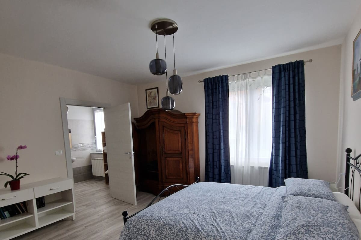 A bedroom with a bed, a dresser, a nightstand, a mirror, and a ceiling light fixture.