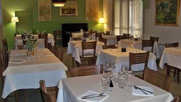 A restaurant with multiple tables set for dining, each with white tablecloths and glassware.