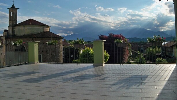 A courtyard with a church, a gate, and a mountain backdrop. - Locanda La Guienda (Torre Canavese)
