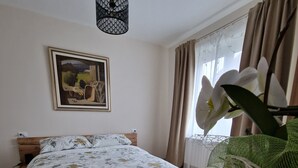 A bedroom with a wooden bed, a hanging light fixture, a framed painting on the wall, and a potted orchid plant. - Locanda La Guienda (Torre Canavese)
