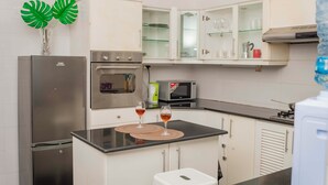 A modern kitchen with stainless steel appliances, white cabinetry, and a black countertop. - Golden Homes  (Nairobi)