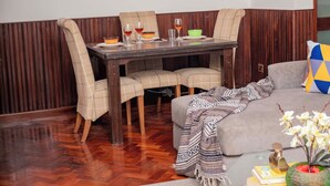 A dining area with a wooden table and chairs, a glass coffee table with books and a vase, and a world map artwork on the wall. - Golden Homes  (Nairobi)