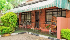 A traditional building with a tiled roof, a striped awning, and a brick facade. - Golden Homes  (Nairobi)